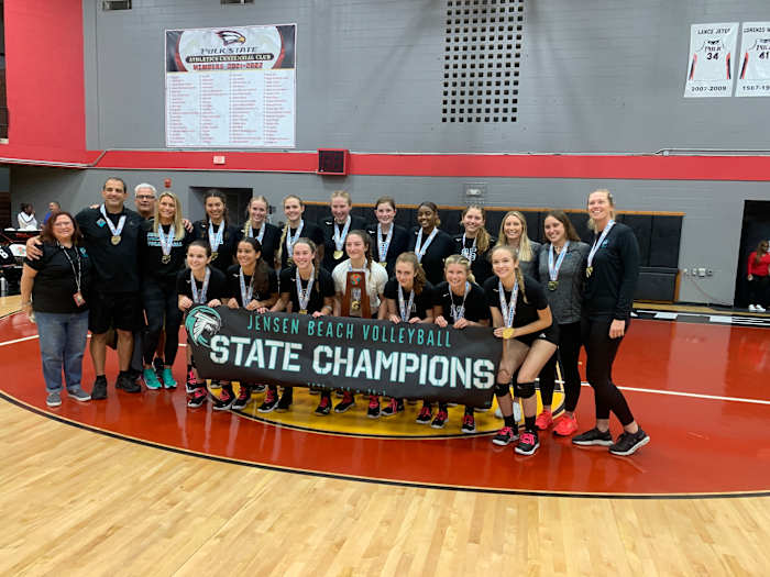 Jensen Beach stands with the state-championship trophy and a banner to match after the Falcons' 25-17 25-15 25-22 victory over Naples Barron Collier in the FHSAA Class 5A volleyball final.